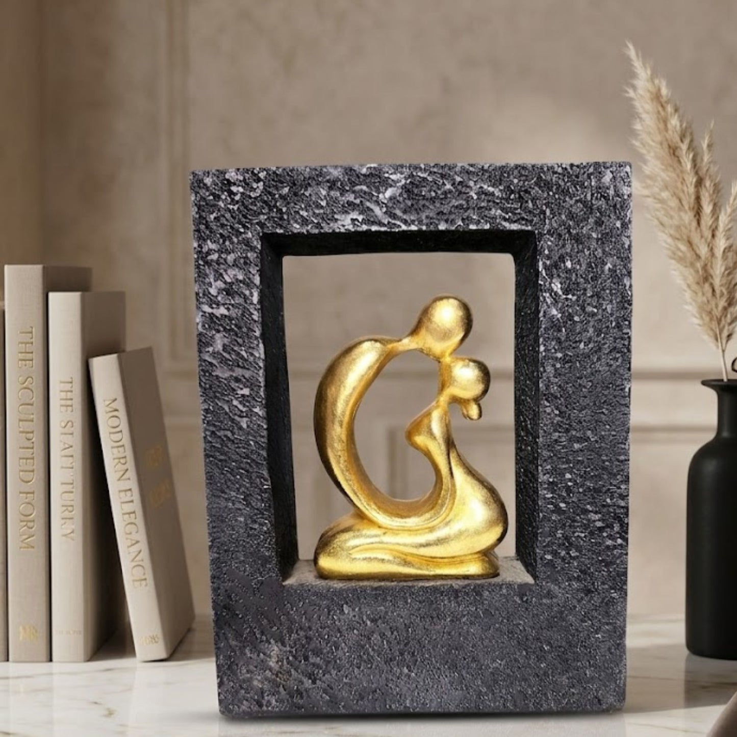 Abstract golden metallic sculpture of an embracing couple placed inside a dark grey textured stone frame for shelf decor.