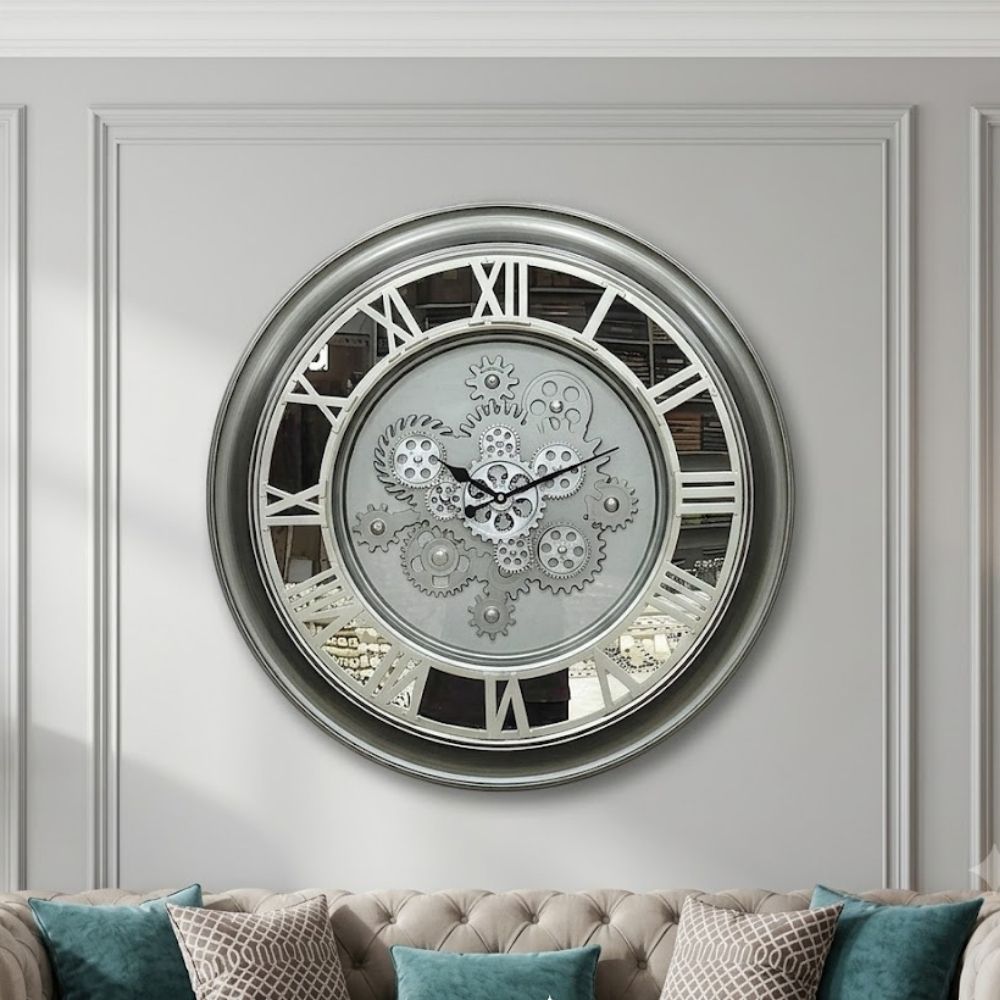 Large round silver skeleton wall clock featuring a metallic grey frame, white Roman numerals, and exposed central silver gears.