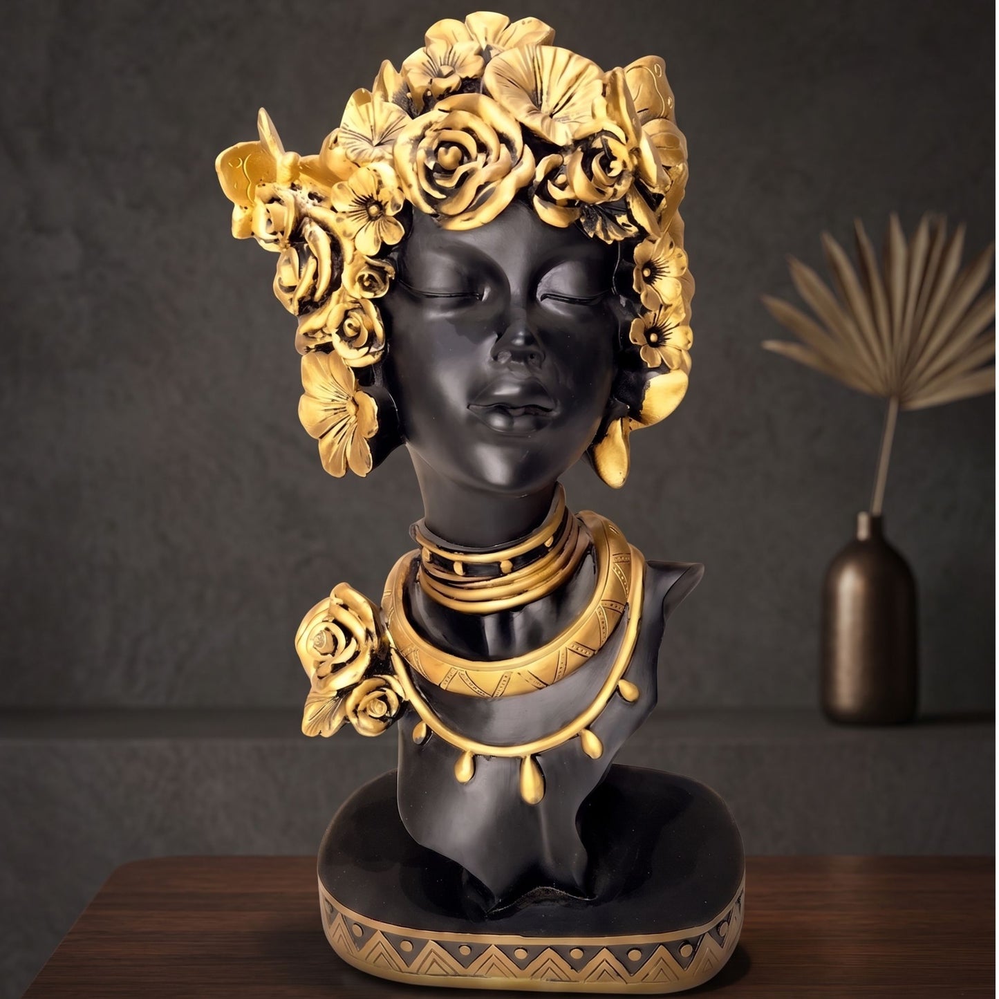 Matte black resin bust sculpture of a serene woman with detailed golden flowers and gold necklace accents.