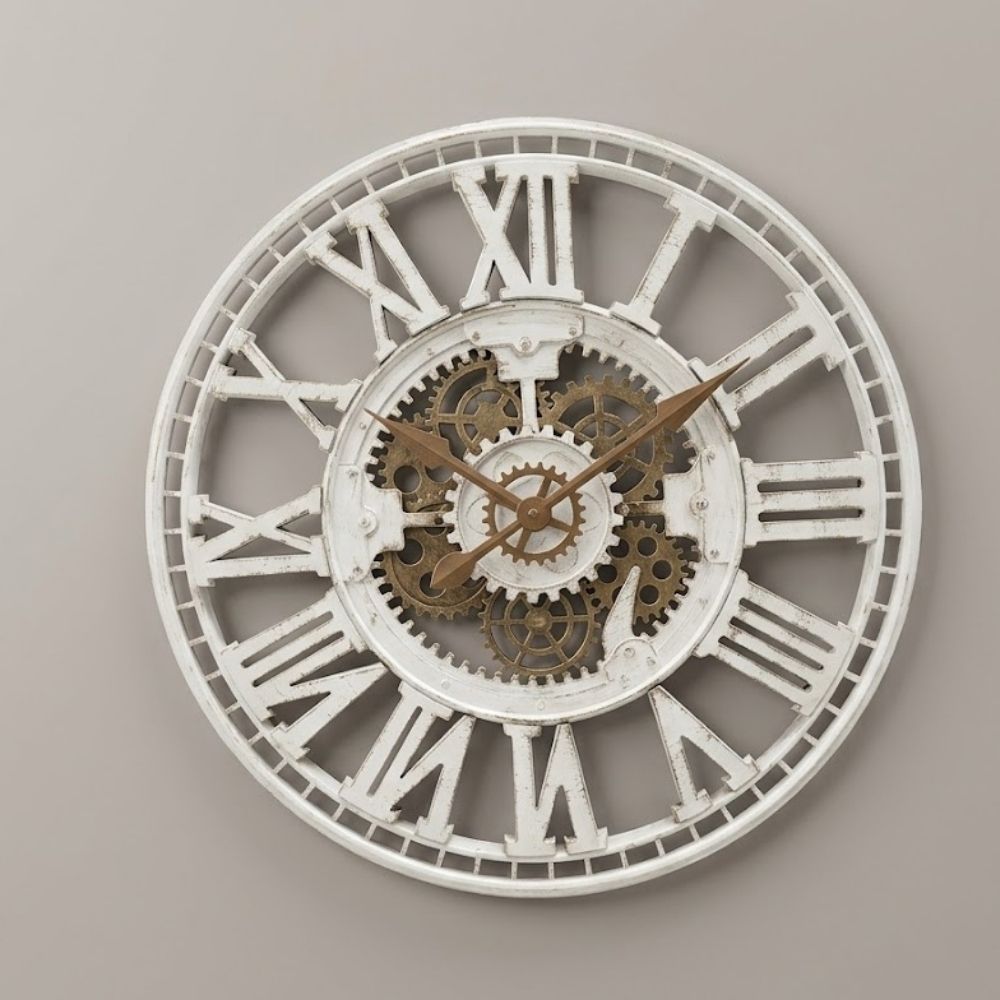 Open-frame white cutout skeleton wall clock featuring weathered distressed finish, Roman numerals, bronze hands, and central bronze mechanical gears.