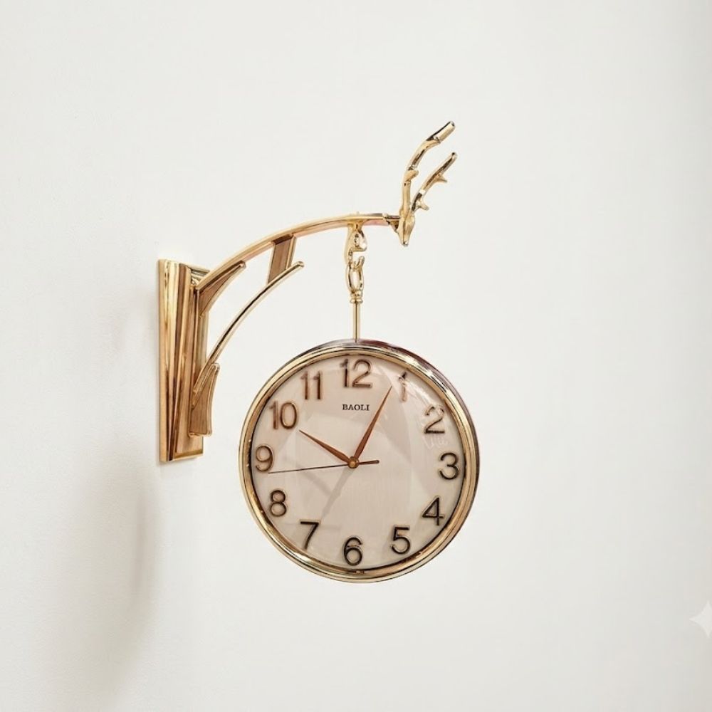 Polished golden wall-mounted hanging clock suspended from a decorative antler bracket with a clean light dial and gold numbers.