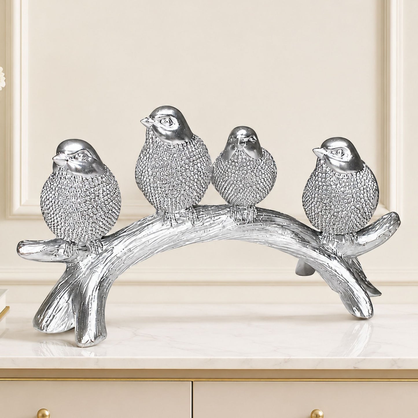 Silver textured sculpture of four birds sitting together on a wooden tree branch for tabletop home decor.