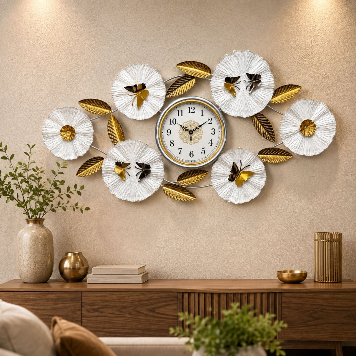 Wide metal wall clock with central gold dial, white textured flower discs with butterflies, and gold leaf accents.