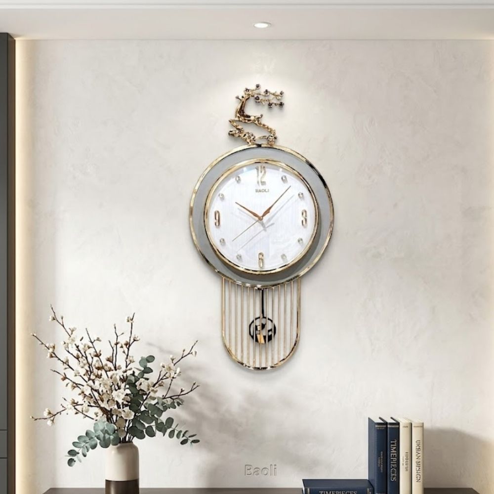 Contemporary round wall clock with a White outer ring, white dial face, topped with a sitting Gray stag sculpture and framed by a gold wire cage pendulum below.