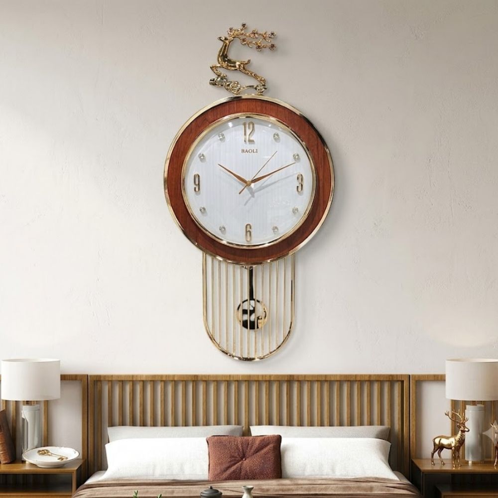 Elegant round wall clock featuring a rich wooden outer ring, textured white dial with crystal hour markers, topped with a golden leaping stag crest and a wire cage pendulum underneath.