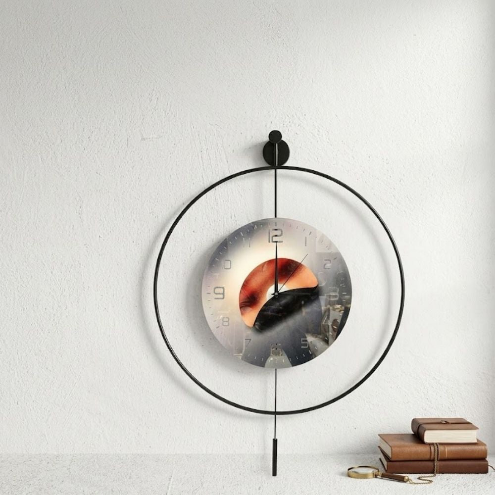 Minimalist round black metal frame wall clock featuring a sunset landscape art dial with a slim vertical pendulum.