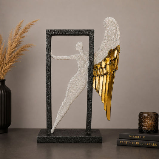Modern abstract silver textured angel figure with gold wings posing inside a black frame for home table decor.