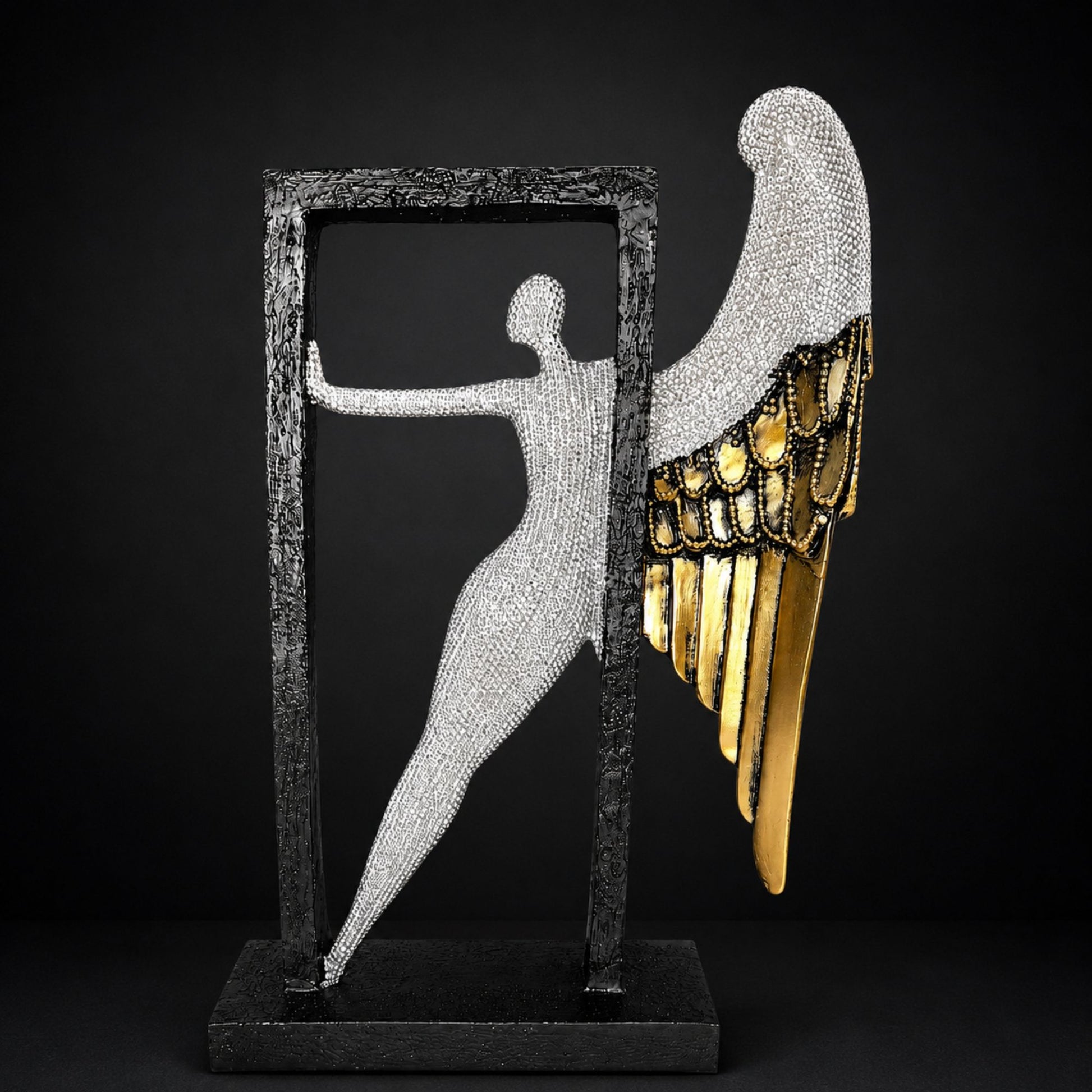 Modern abstract silver textured angel figure with gold wings posing inside a black frame for home table decor.