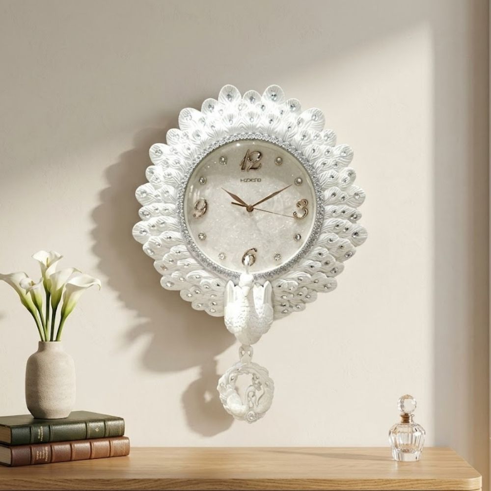 Ornamental white wall clock styled with a radiant swan feather border embedded with rhinestones, central glitter dial with gold numerals, and a hanging white swan pendulum.