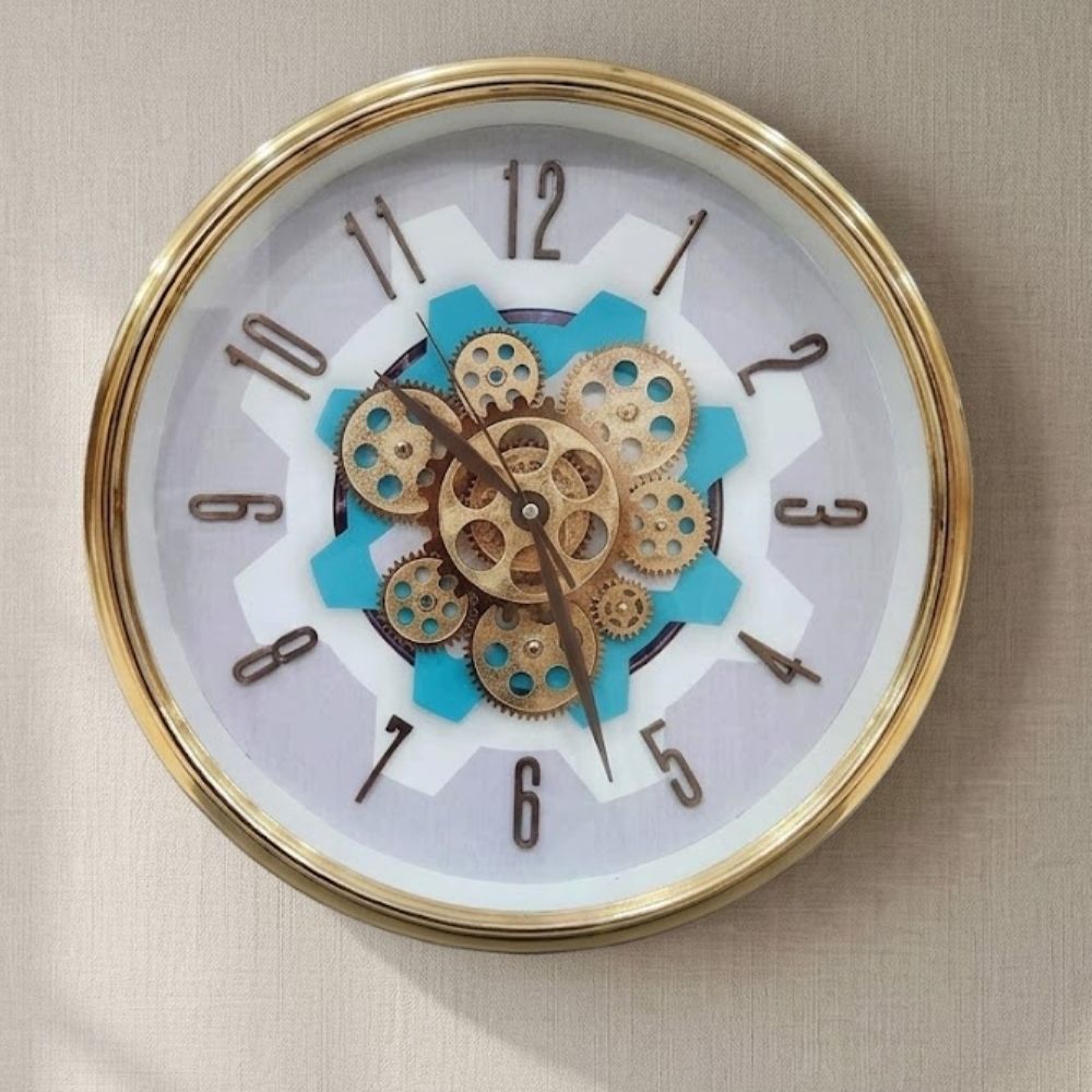 Round wall clock featuring a golden metallic rim, white dial, dark numbers, and central brass gears set over a vibrant turquoise backdrop.