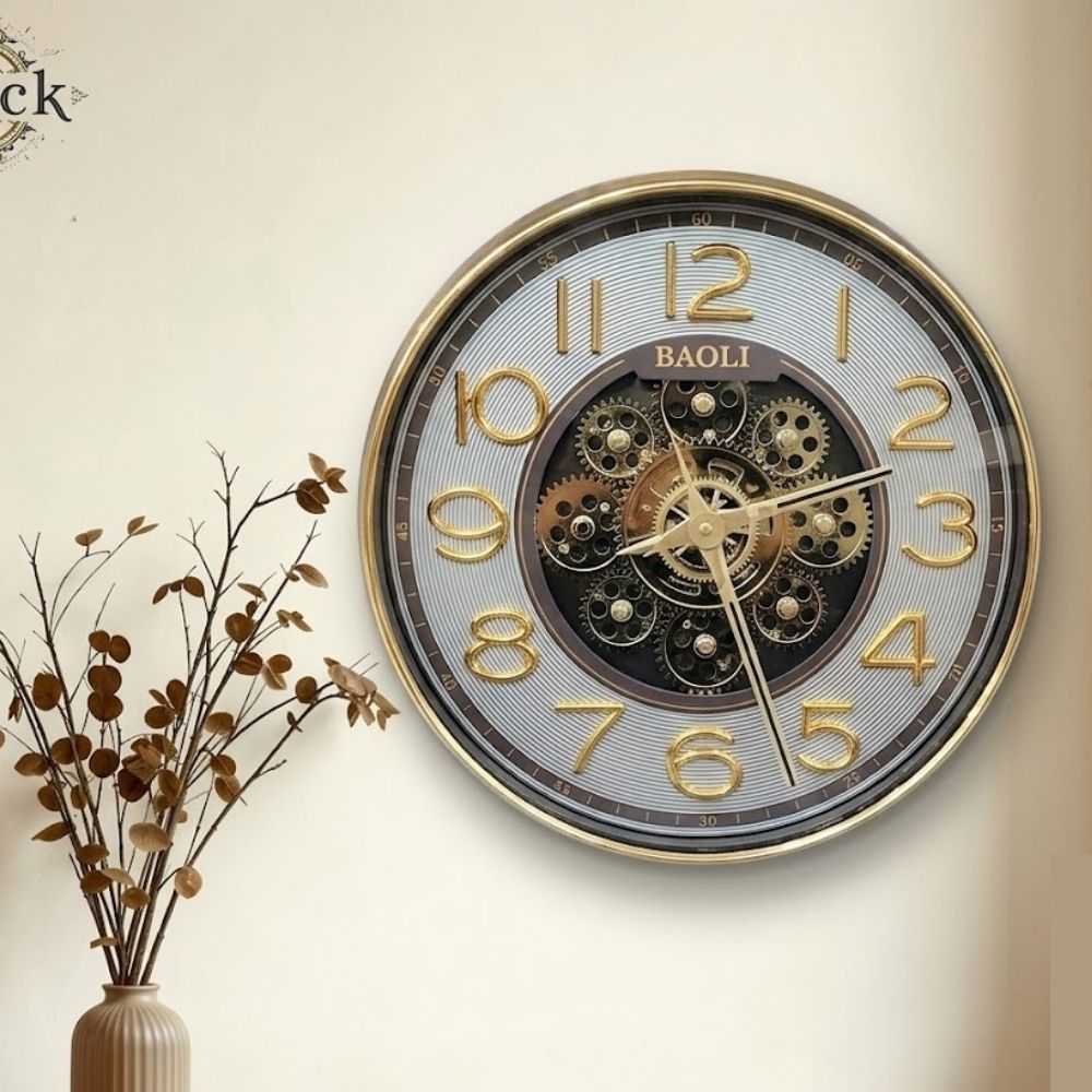 Round wall clock featuring a silver textured dial, bold golden numbers, a golden rim, and exposed central mechanical gears.