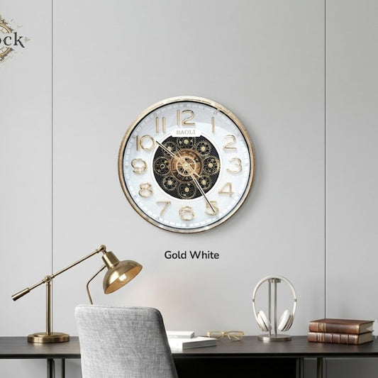 Round wall clock with a white outer ring, bold golden numbers, a golden rim, and exposed central mechanical gears.