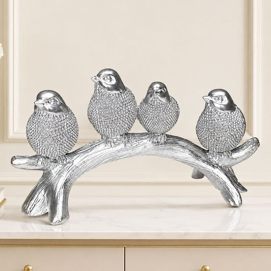 Silver textured sculpture of four birds sitting together on a wooden tree branch for tabletop home decor.