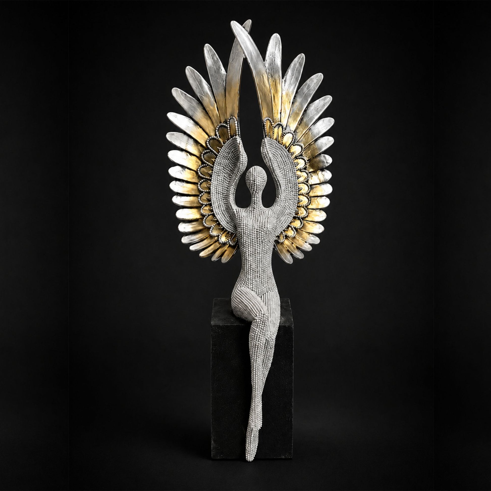 Textured silver seated angel figure with large gold and silver feathered wings perched on a black pedestal base.