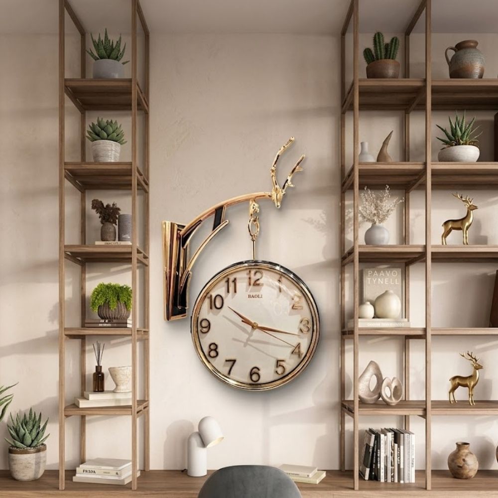 Wall-mounted hanging round clock with a golden frame, suspended from a decorative stag antler bracket set against a modern shelving background.